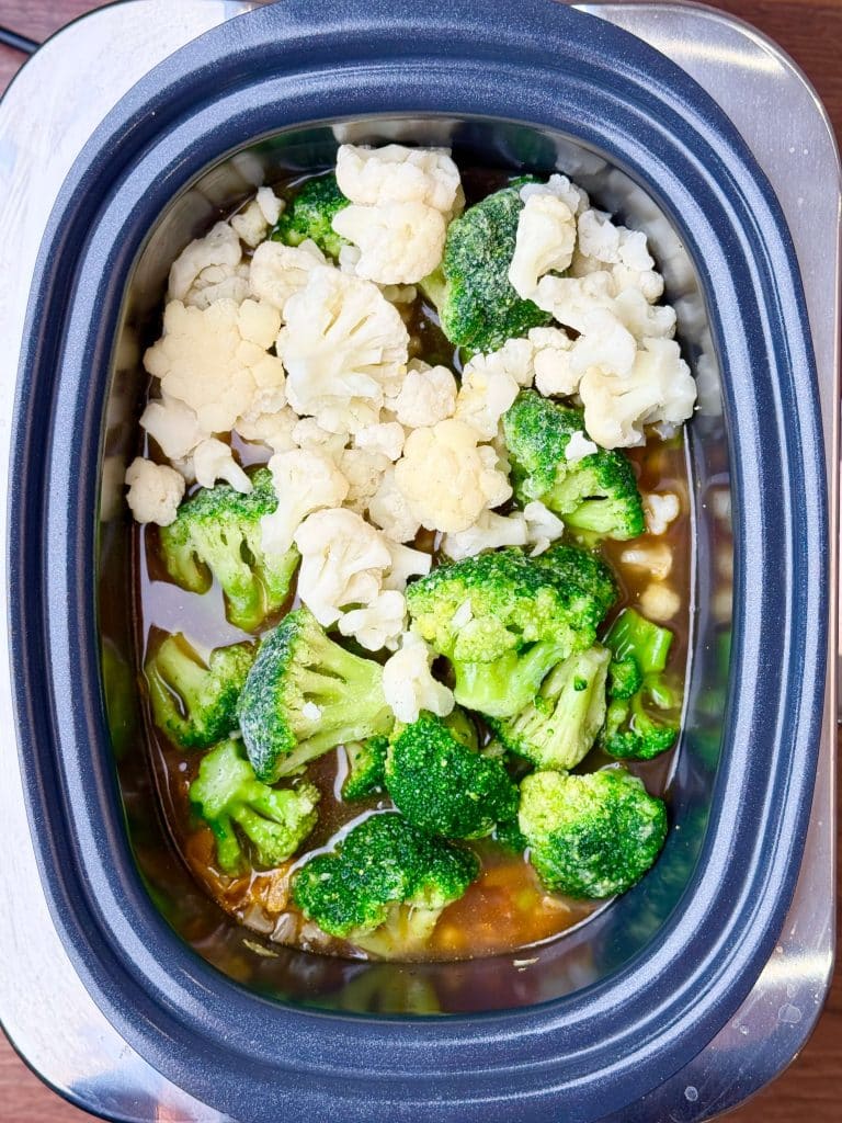 Broccoli and cauliflower florets with broth in a slow cooker
