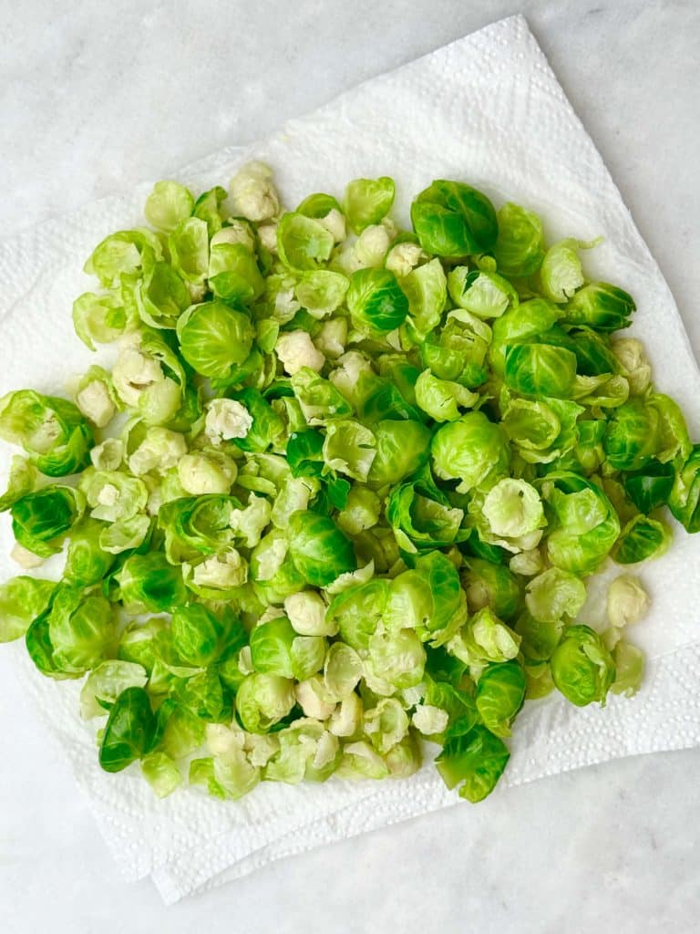 Blanched Brussels sprouts leaves drying on a paper towel.