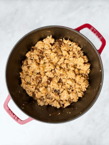 Ground chicken sausage cooking in a Dutch oven until golden and crumbly.