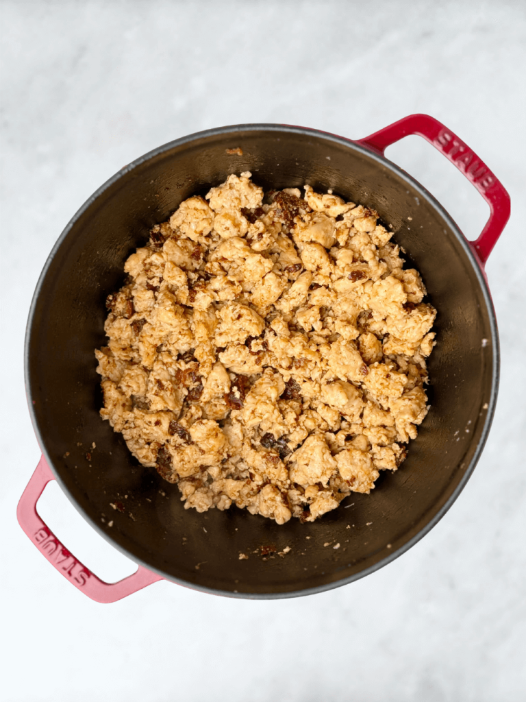 Ground chicken sausage cooking in a Dutch oven until golden and crumbly.