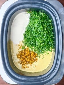 Slow cooker spiced chickpea stew with kale, coconut milk, and chickpeas before stirring together.
