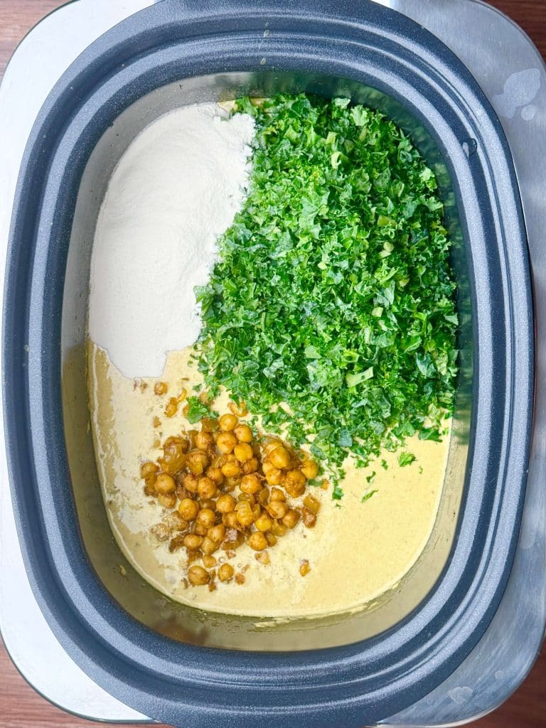 Slow cooker spiced chickpea stew with kale, coconut milk, and chickpeas before stirring together.