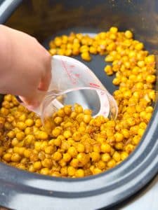 Chickpeas coated in turmeric and spices cooking in crockpot for spiced chickpea stew.