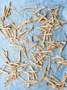 Homemade baked tortilla strips on parchment paper for topping crockpot birria soup.
