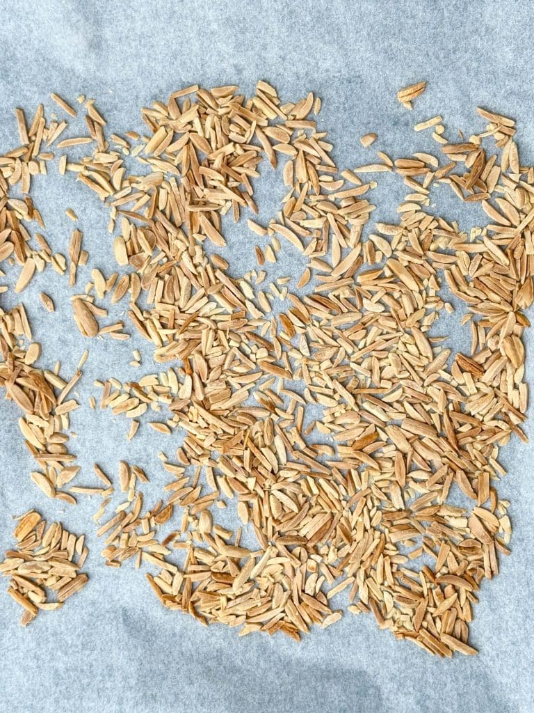 Oven-toasted almond slivers cooling on a parchment-lined baking sheet.