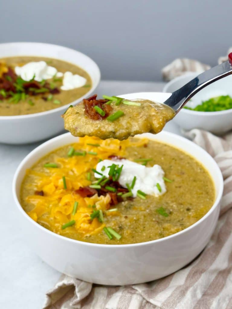 Spoonful of creamy broccoli cheddar soup with bacon and chives
