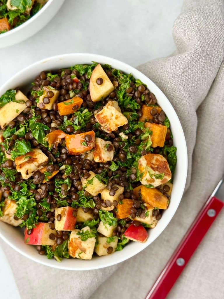 High-protein fall salad featuring black lentils, apple, roasted sweet potatoes, and halloumi cheese for a cozy meal.