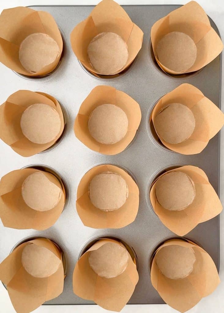 Overhead shot of a muffin tin lined with tall brown tulip liners, ready for baking high protein pumpkin breakfast muffins.