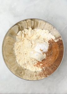Bowl of dry ingredients including protein powder, oat flour, baking powder, and pumpkin spice for high protein pumpkin oat muffins.