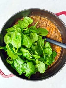 Fresh baby spinach stirred into a pot of lentil soup for extra nutrients and color.