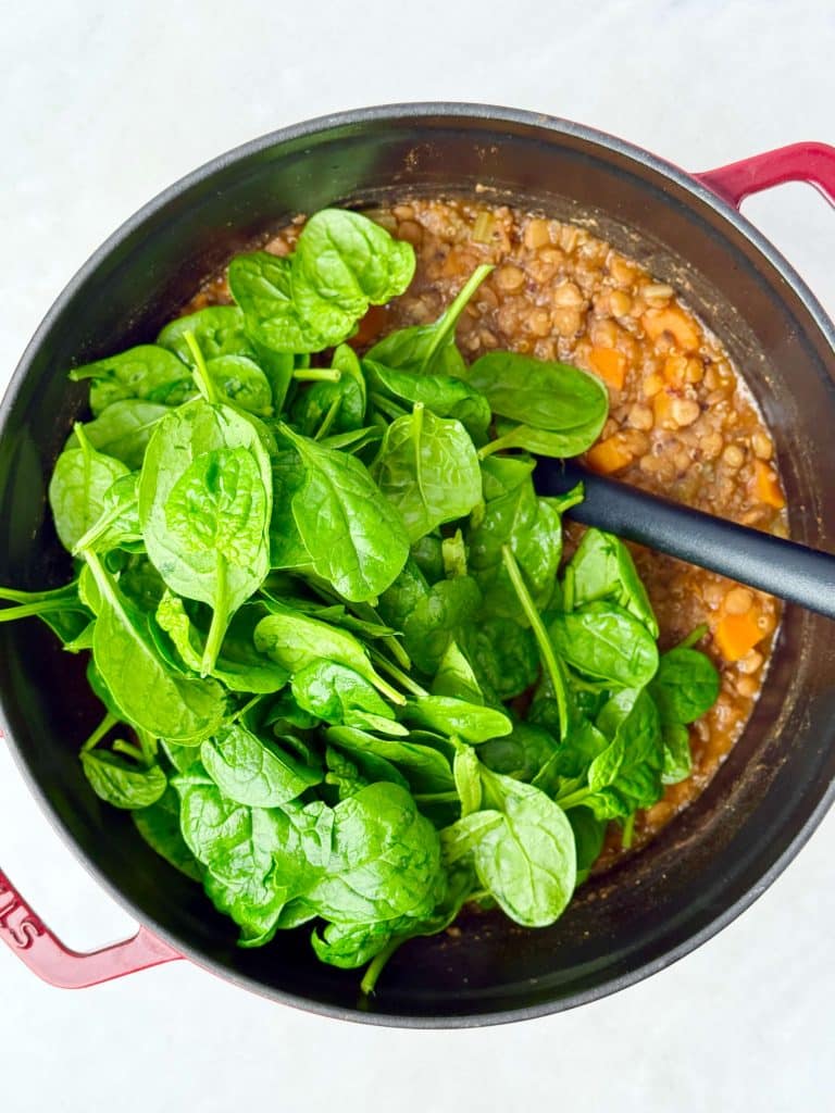 Fresh baby spinach stirred into a pot of lentil soup for extra nutrients and color.