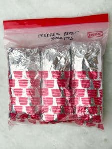 Foil-wrapped high protein freezer breakfast burritos stored in a labeled zip-lock bag for easy make-ahead meal prep.