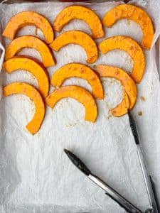 Thin slices of kabocha squash tossed in miso marinade, arranged on a parchment-lined sheet pan