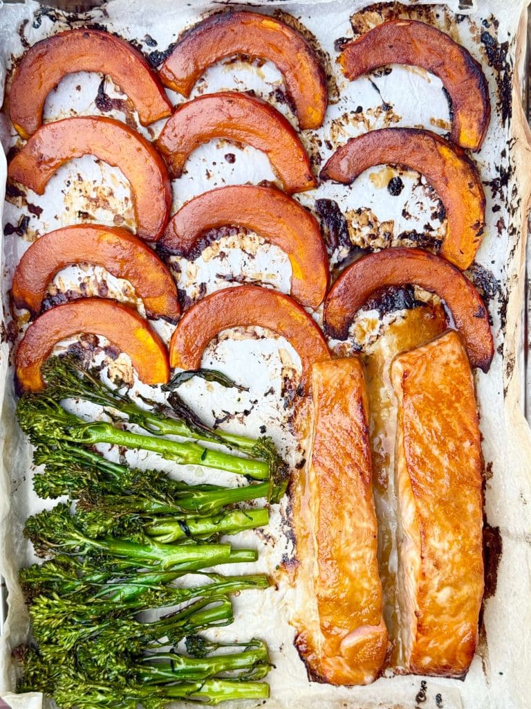 Roasted miso salmon, kabocha squash, and broccolini on a parchment-lined sheet pan, caramelized and golden