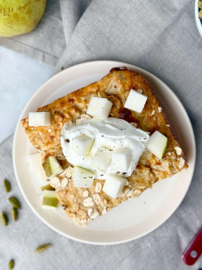 Overhead view of pear cardamom baked oat bar topped with yogurt and fresh pear cubes.