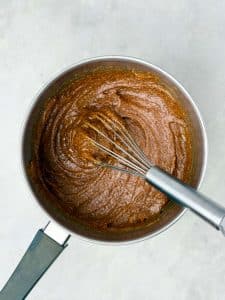 Bowl of almond butter and maple syrup whisked together for the wet mixture in homemade protein granola.