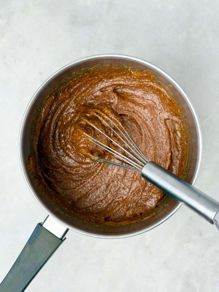Bowl of almond butter and maple syrup whisked together for the wet mixture in homemade protein granola.