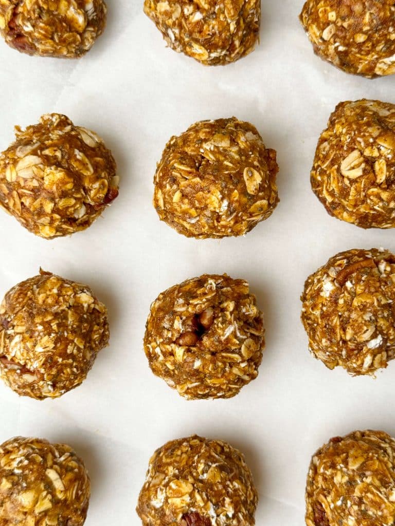 Pumpkin spice protein balls in neat rows on white parchment paper.