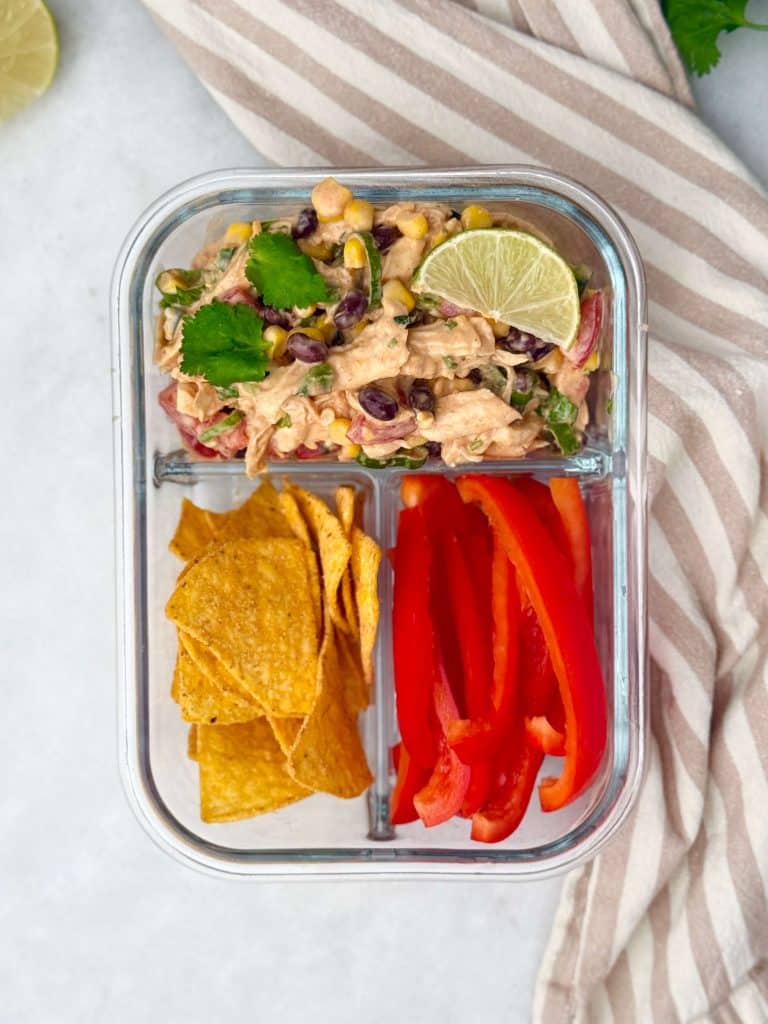 Meal prep container with Southwest Chicken Salad, tortilla chips, and sliced red bell peppers.