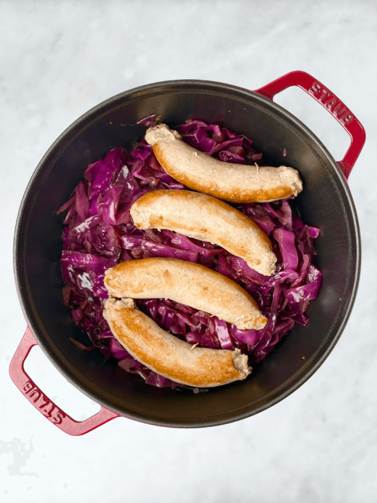 One-pot red cabbage with sausage in a Dutch oven, a rustic sweet and sour cabbage dinner