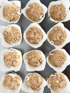 Unbaked apple cinnamon muffin batter in liners topped with cinnamon protein crumble before baking.