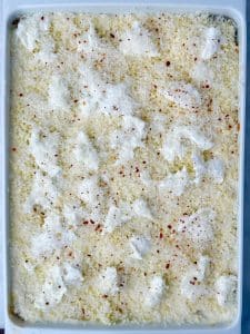 Unbaked lasagna topped with torn fresh mozzarella, grated Parmesan, and red pepper flakes before going into the oven.