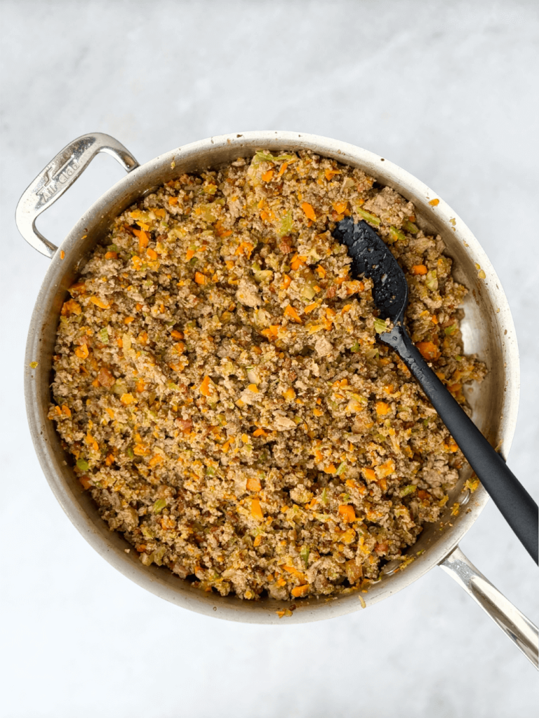 Ground meat and chopped vegetables simmering together in a pan for bolognese ragu.