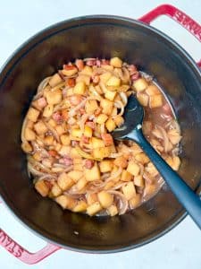 Sautéed apples, onions, and bacon in a Dutch oven for German red cabbage with sausage
