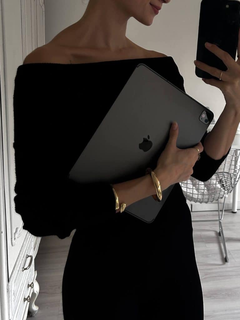 Woman in a black outfit holding an iPad, representing focus and ambition for a career vision board theme.