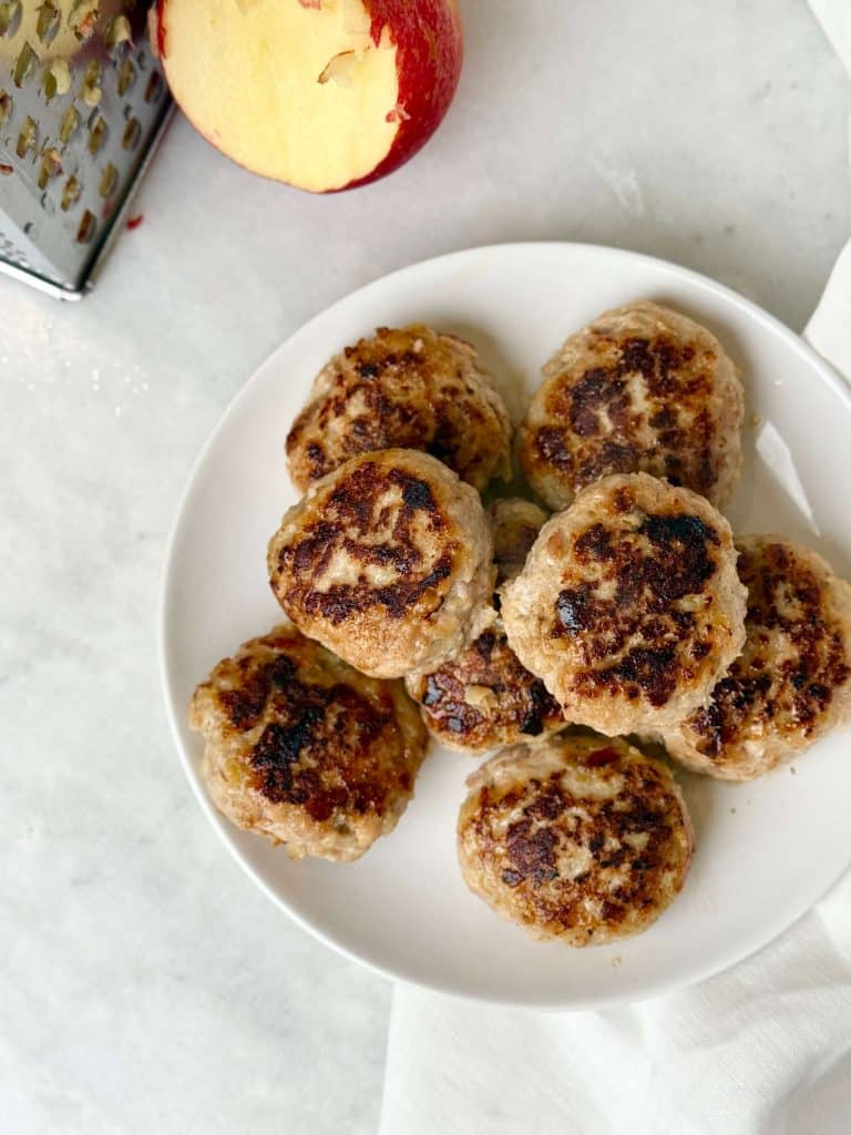 Plate of golden brown chicken apple sausage patties made from ground chicken and grated apple