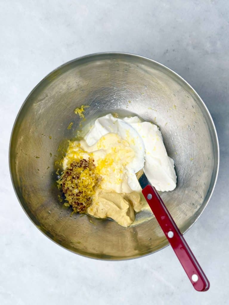 Greek yogurt, Dijon mustard, grainy mustard, and lemon zest in a mixing bowl for apple walnut chicken salad dressing.