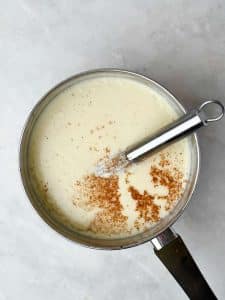 Creamy béchamel sauce in a saucepan with freshly grated nutmeg on top, ready for layering in lasagna.