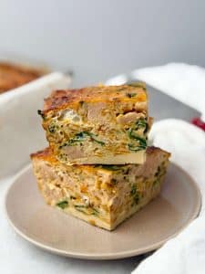 Close-up of thick, golden slices of sausage and sweet potato breakfast casserole showing fluffy egg texture.