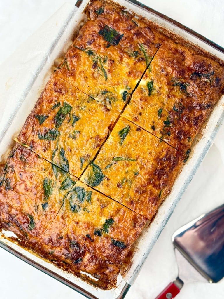 Overhead view of a sliced sweet potato and spinach breakfast casserole baked in a glass dish.