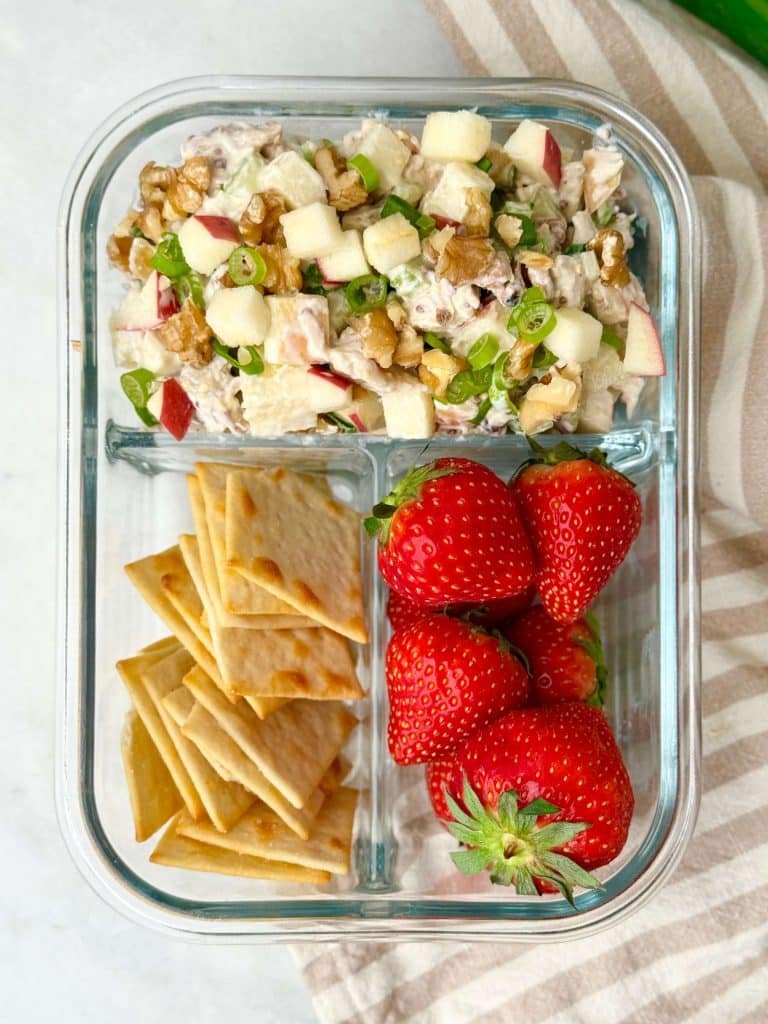 Apple walnut chicken salad meal prep container with crackers and fresh strawberries for an easy healthy lunch.