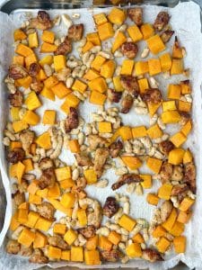 Sheet tray of roasted butternut squash, white beans, and sausage for a farro and sausage salad recipe.