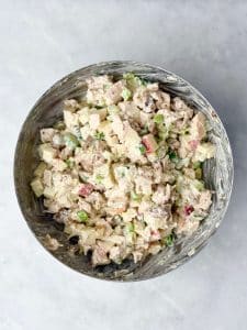 Creamy apple walnut chicken salad mixed in a bowl with diced chicken, apples, celery, and green onions.
