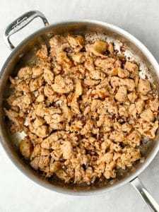 Crumbled breakfast sausage browning in a stainless steel skillet for a dairy-free breakfast casserole.