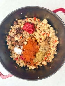 Adding tomato paste and spices to ground turkey mixture for high protein low calorie chili recipe.