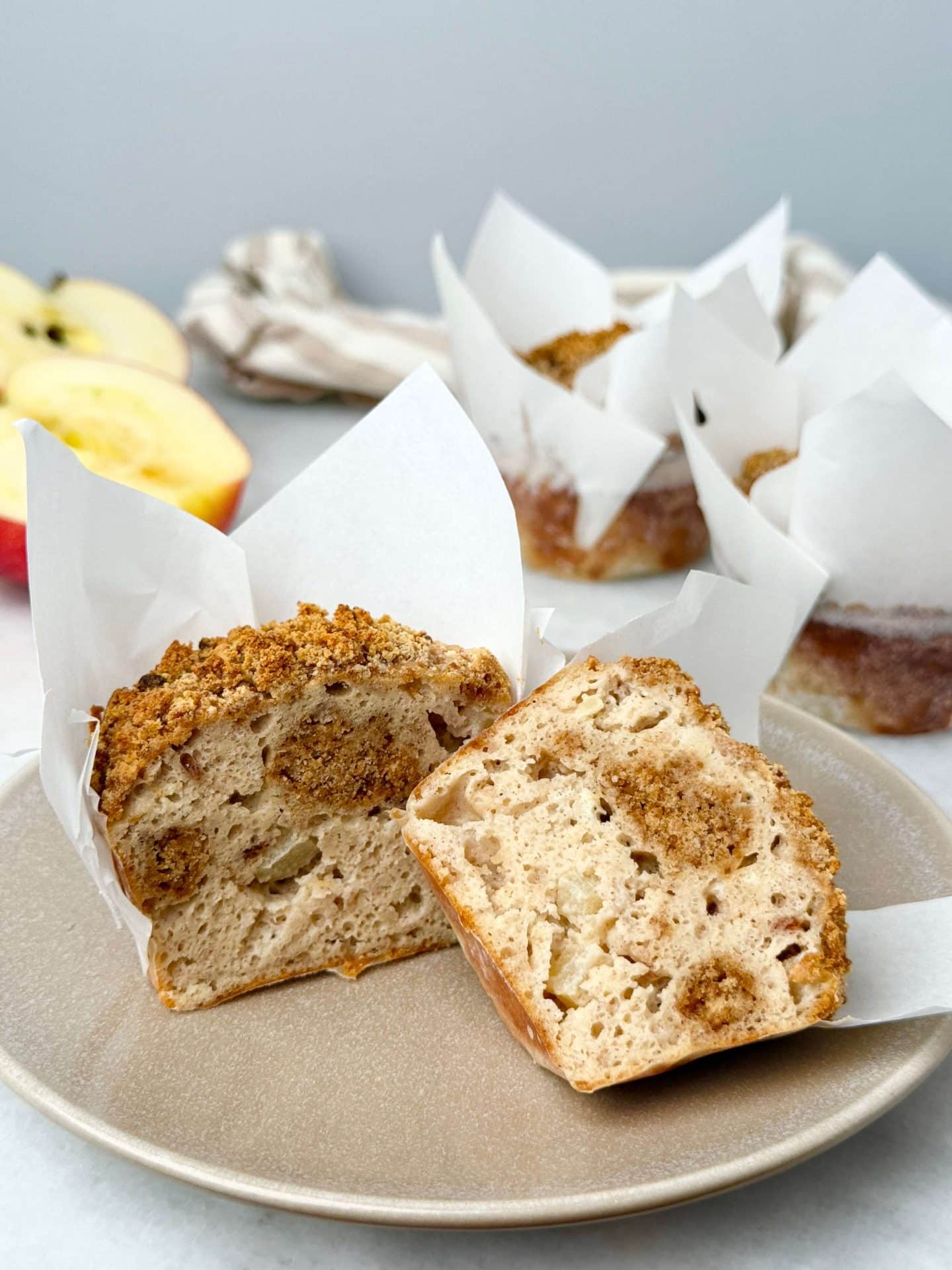 High-protein apple cinnamon muffins sliced in half to show soft, fluffy texture with baked crumble and apple pieces.