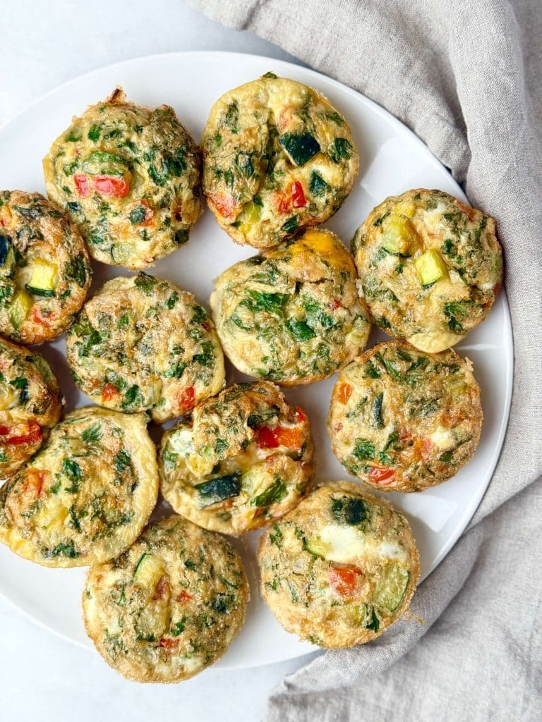 Veggie-loaded breakfast frittata cups on a white plate made with kale, bell pepper, and zucchini