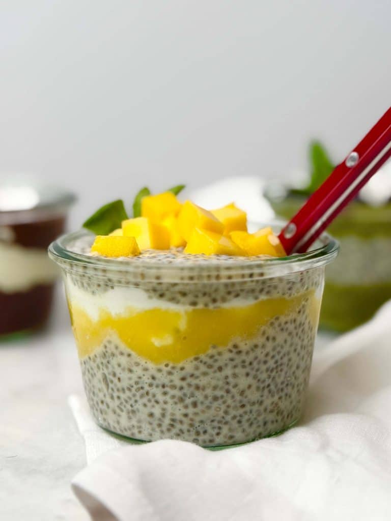 Dairy-free chia seed pudding layered with mango puree and coconut yogurt in a glass jar.