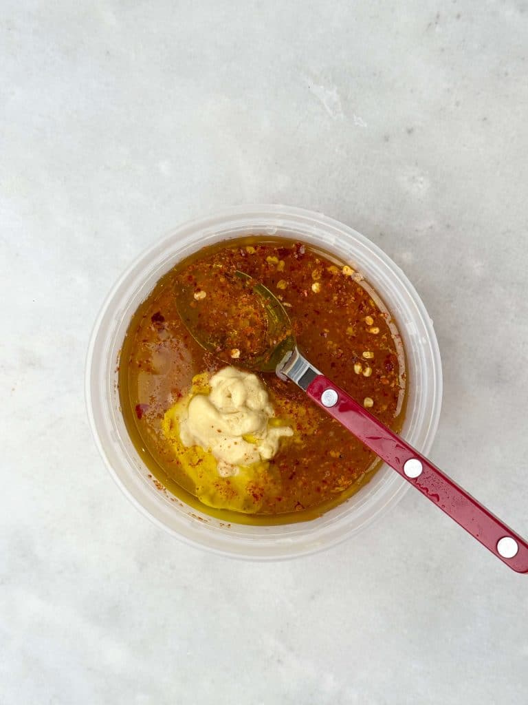 Bowl of honey lemon vinaigrette with mustard and red pepper flakes, ready to drizzle over a fall farro salad.