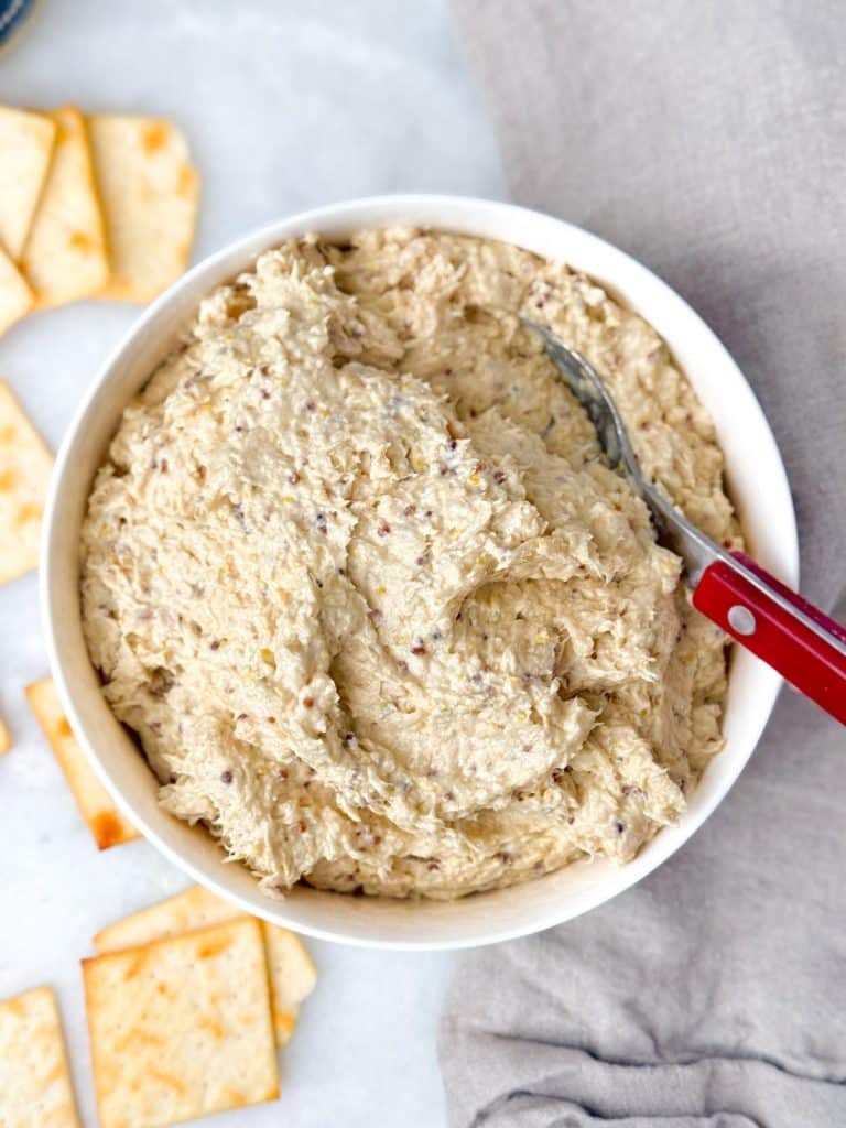 Overhead view of creamy chicken salad in a white bowl with pita crackers