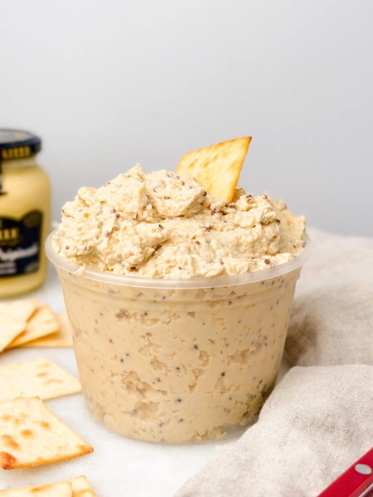 Honey mustard chicken salad scooped into a deli container with a cracker on top