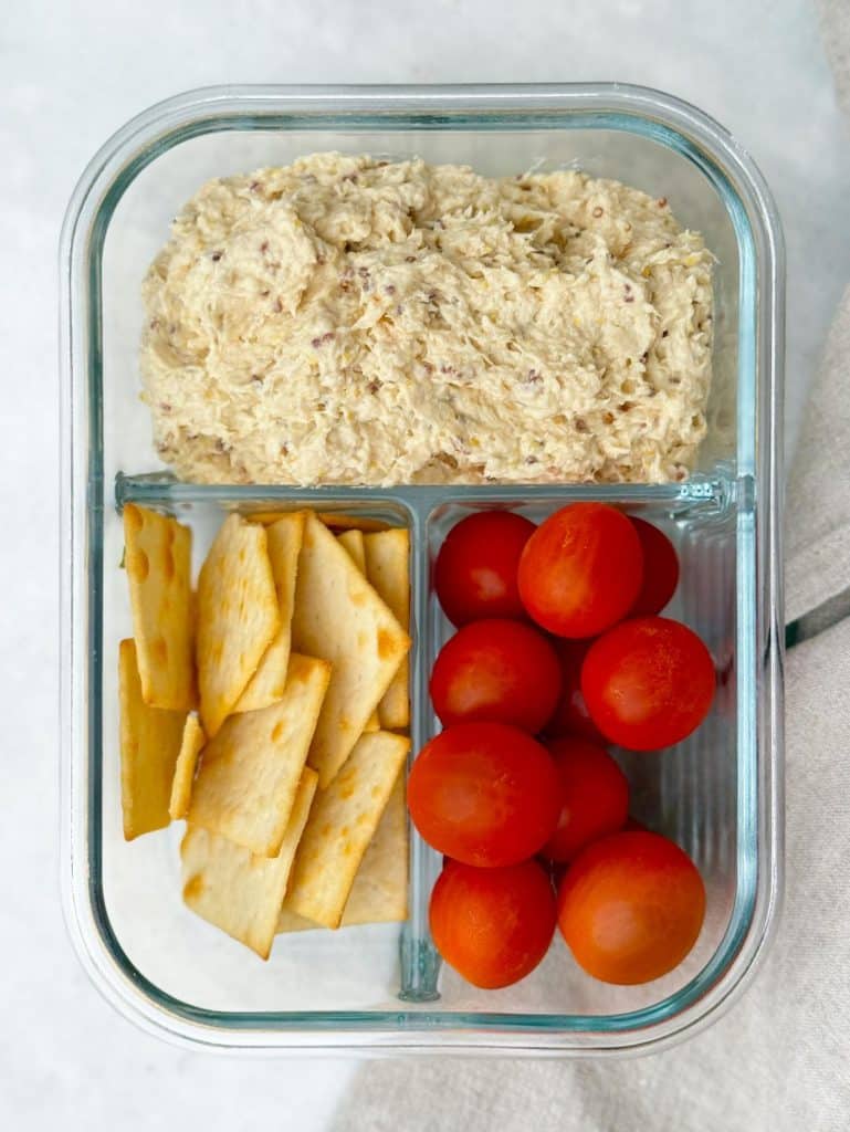 Honey mustard chicken salad meal prep container with crackers and cherry tomatoes