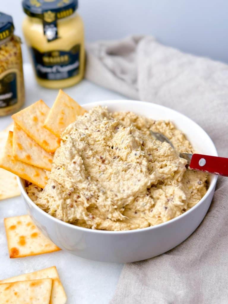 Bowl of honey mustard chicken salad with Maille dijon mustard jars and crackers