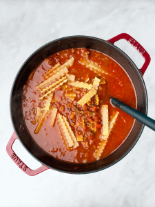 Broken lasagna noodles cooking in tomato broth for easy one-pot lasagna soup.
