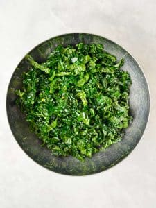 Bowl of freshly massaged kale with olive oil, ready to mix into warm butter bean salad.