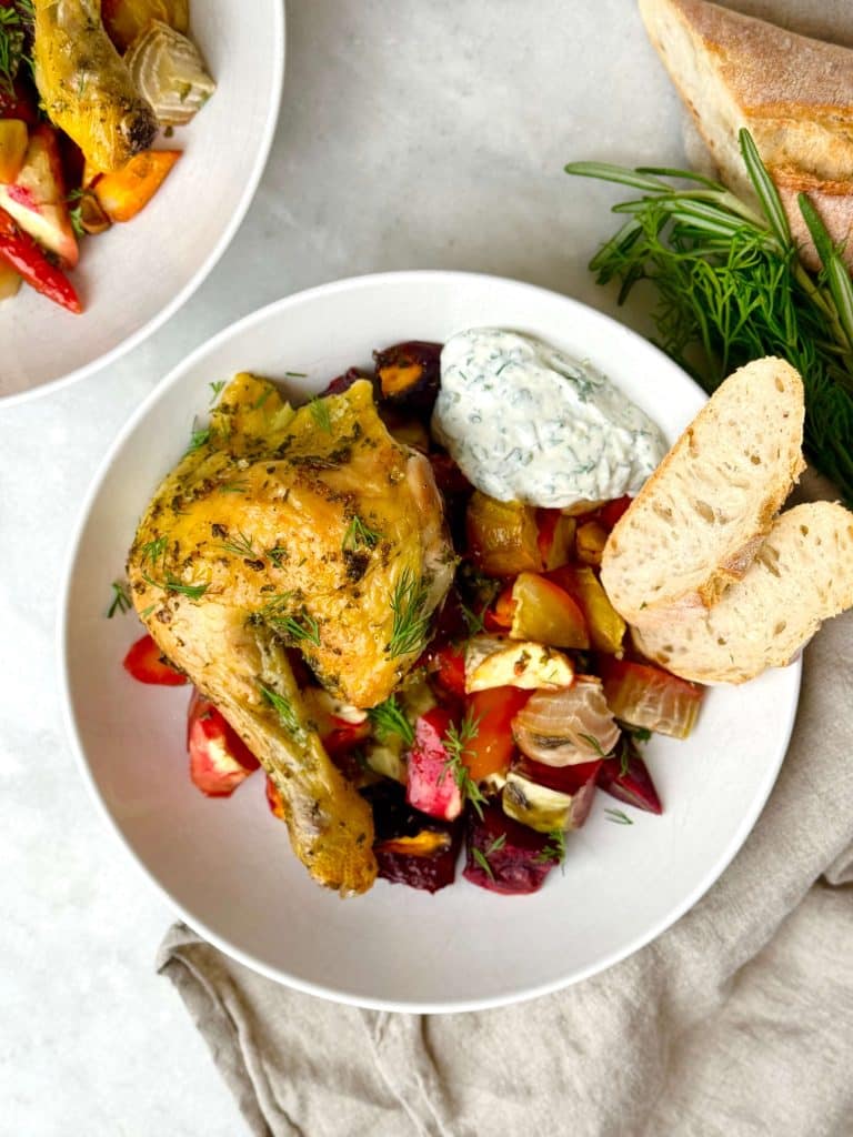 Overhead view of oven roasted spatchcock chicken with roasted beets, carrots, parsnips, and yogurt herb sauce.